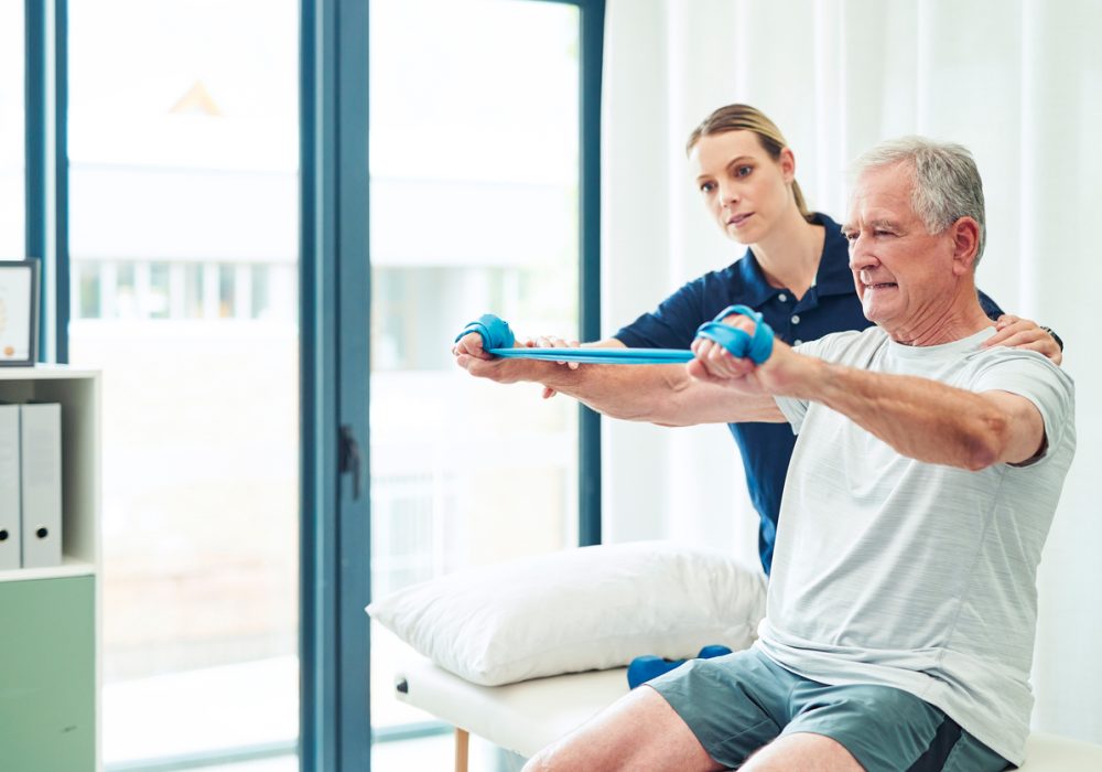 Physiotherapy doctor, senior patient and band for stretching, physical therapy and orthopedic health. Physiotherapist, chiropractor and nurse help elderly man, osteoporosis and surgery rehabilitation